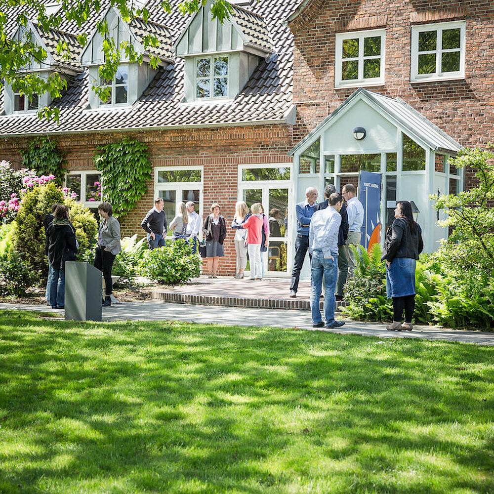 Menschen unterhalten sich vor der Nordsee Akademie.